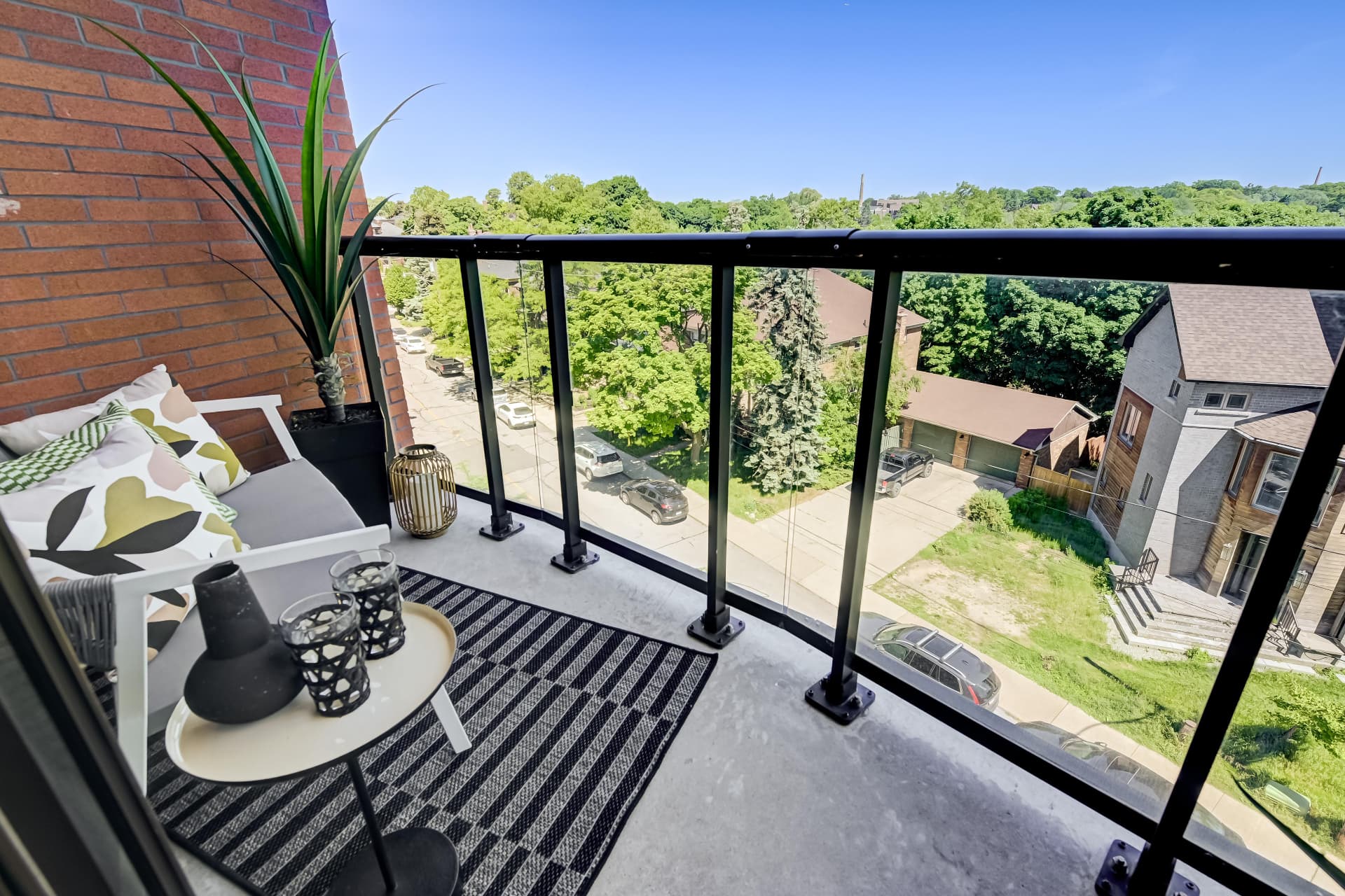 Private balcony with seating, glass railing and leafy street views