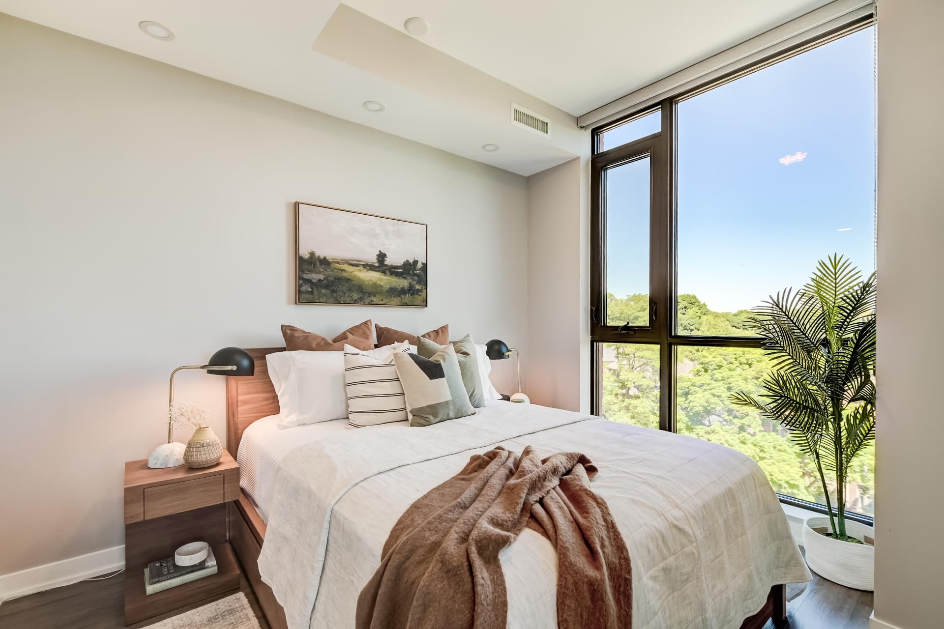 Primary bedroom with floor-to-ceiling window and treetop views