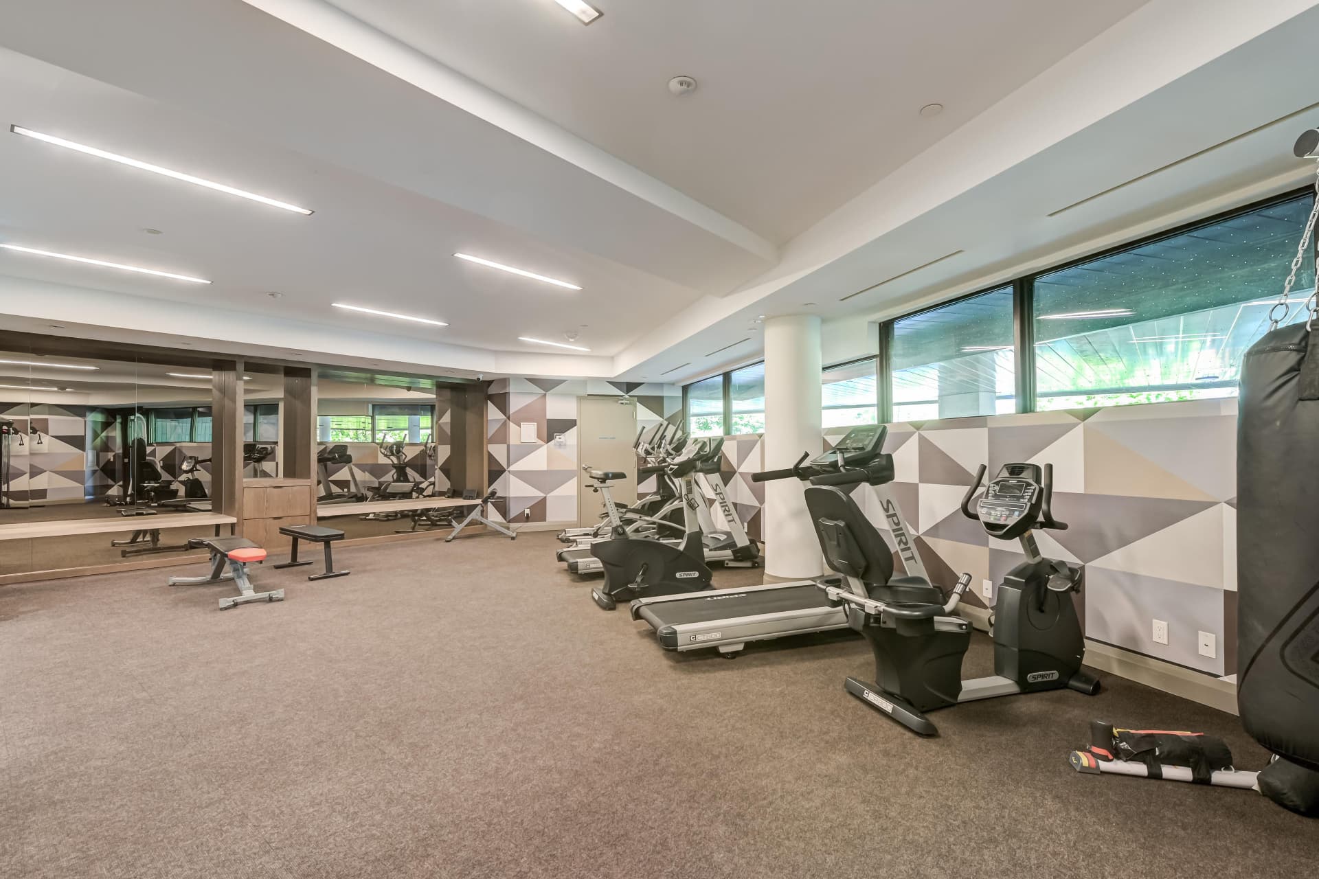 Gym with mirrored wall, treadmills, bikes and heavy bag